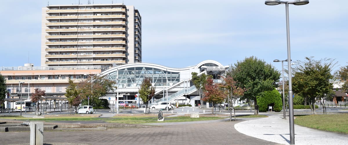 A modern urban area with a tall building, a curved glass structure, and a paved walkway.