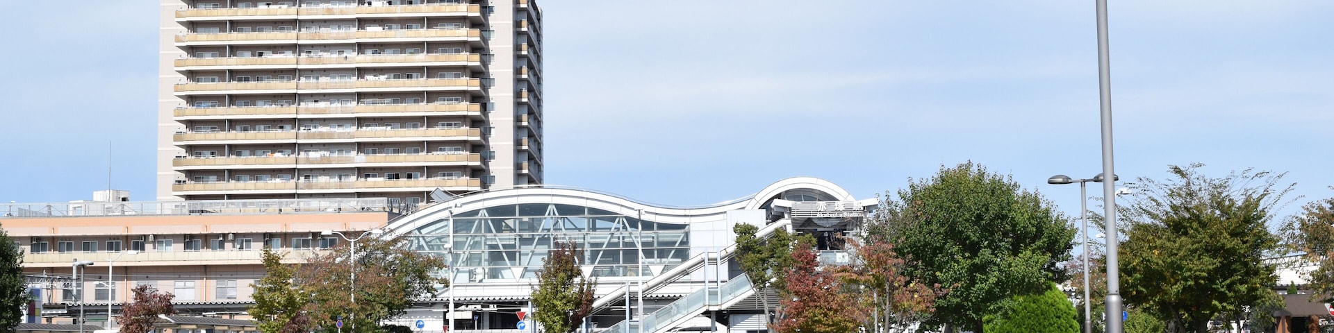 A modern urban area with a tall building, a curved glass structure, and a paved walkway.