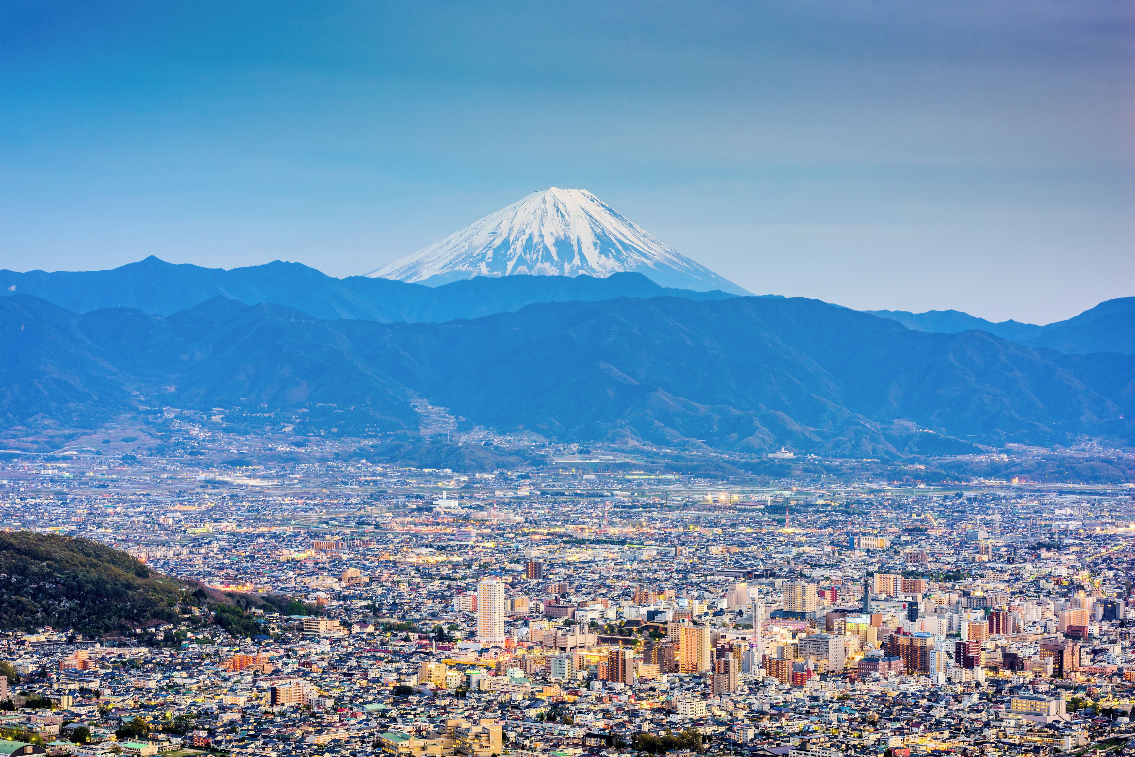 A cityscape with a prominent snow-capped mountain in the background.