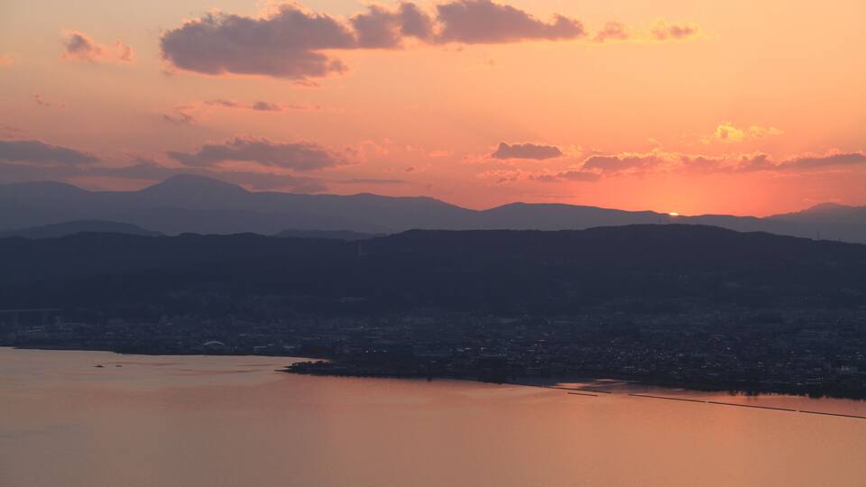 A sunset over a cityscape with mountains in the background.