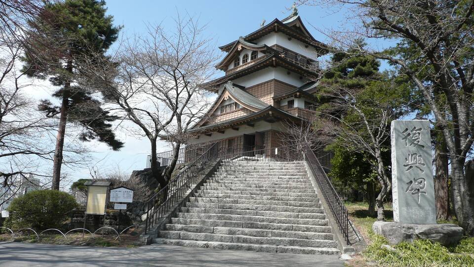 A traditional Japanese building with a stone staircase leading up to it.