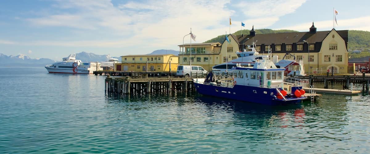 Un puerto con barcos, un muelle y edificios al fondo.