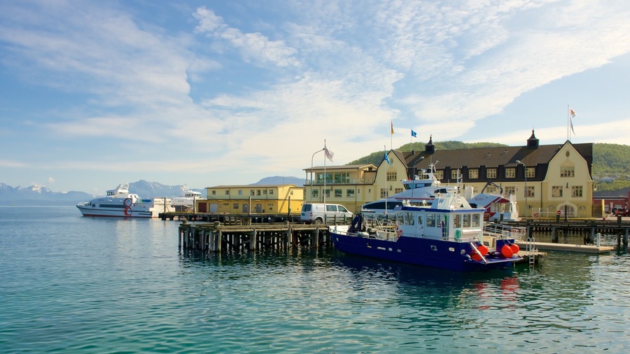 Un puerto con barcos, un muelle y edificios al fondo.