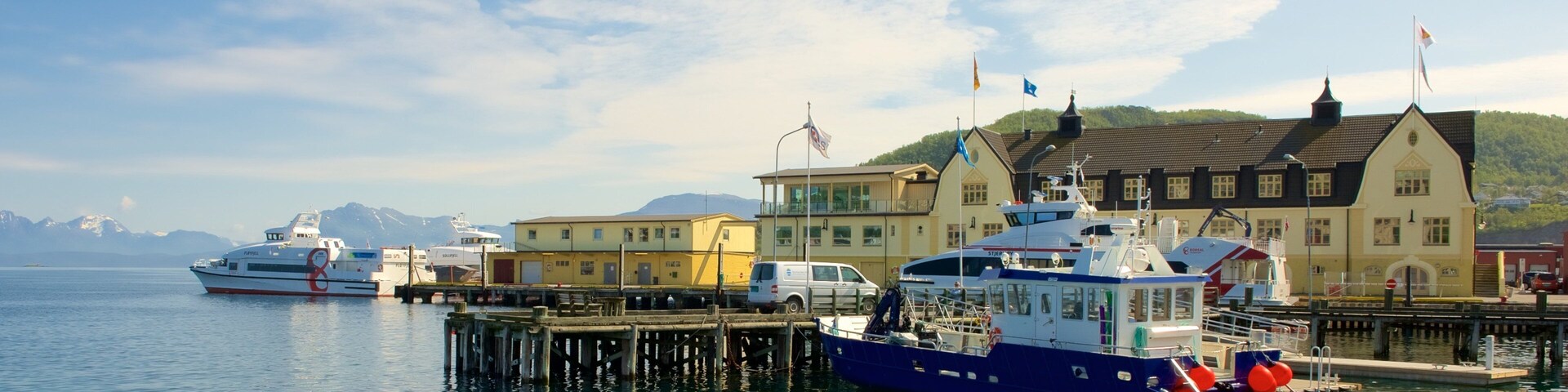Un puerto con barcos, un muelle y edificios al fondo.