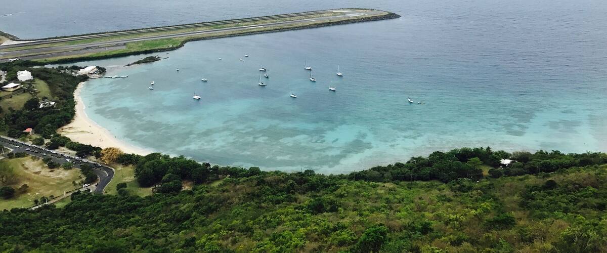 A coastal area with a beach, boats, and a runway extending into the sea.