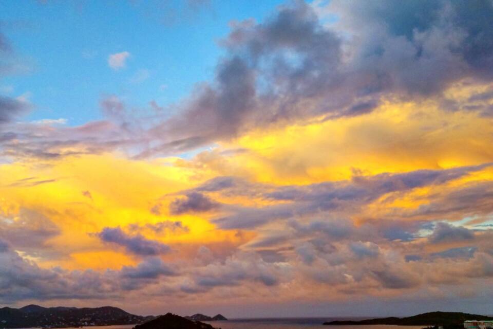 A sunset over a harbor with boats and a distant island.
