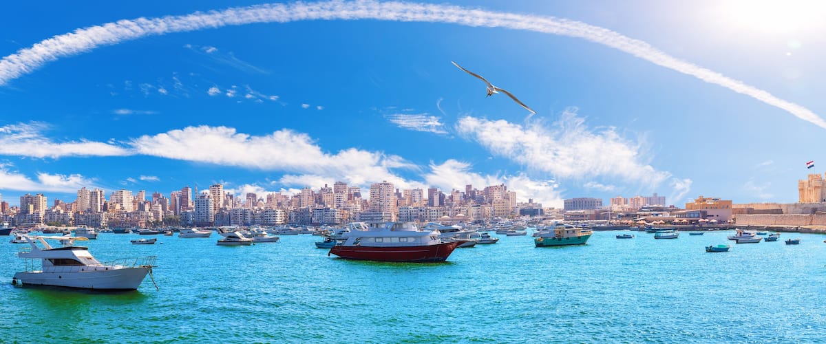 Sea panorama of Alexandria with boats, old city buildings and the citadel of Qaitbay, Egypt