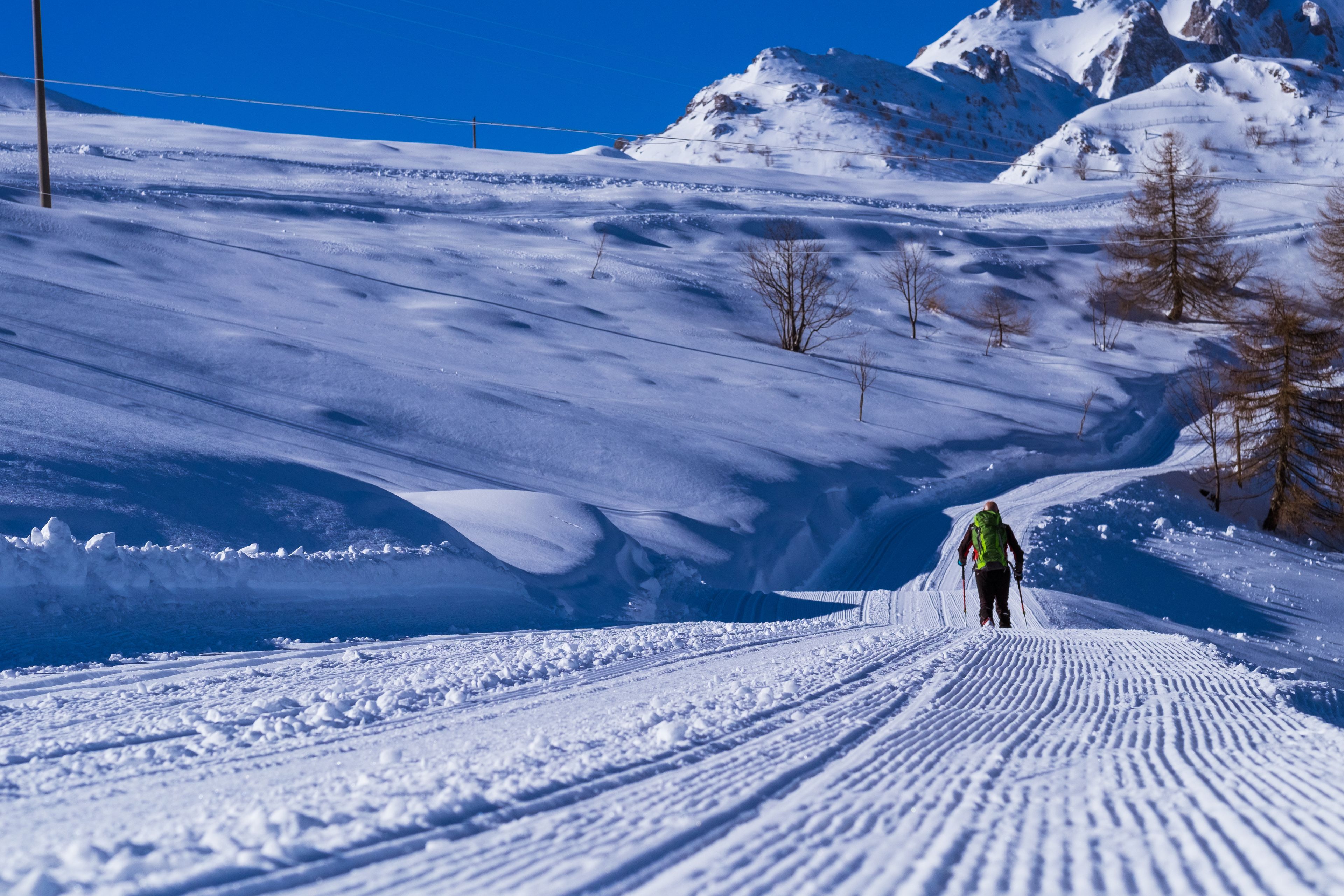 A snowy mountain path with a skier descending.