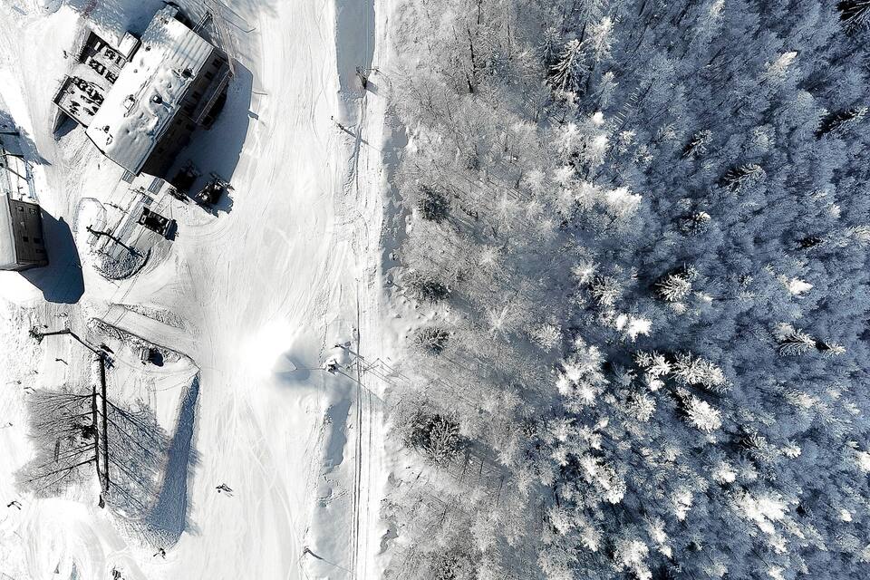 Un paysage enneigé avec une route, des bâtiments et des arbres.