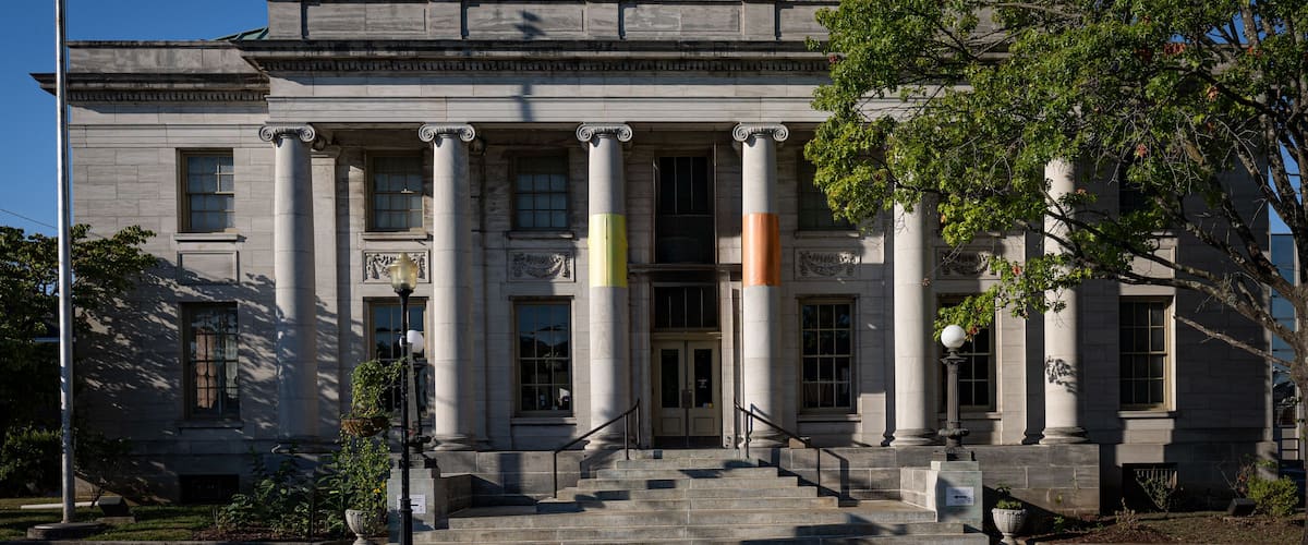 A stately building with large columns, a grand entrance, and steps leading up to it.