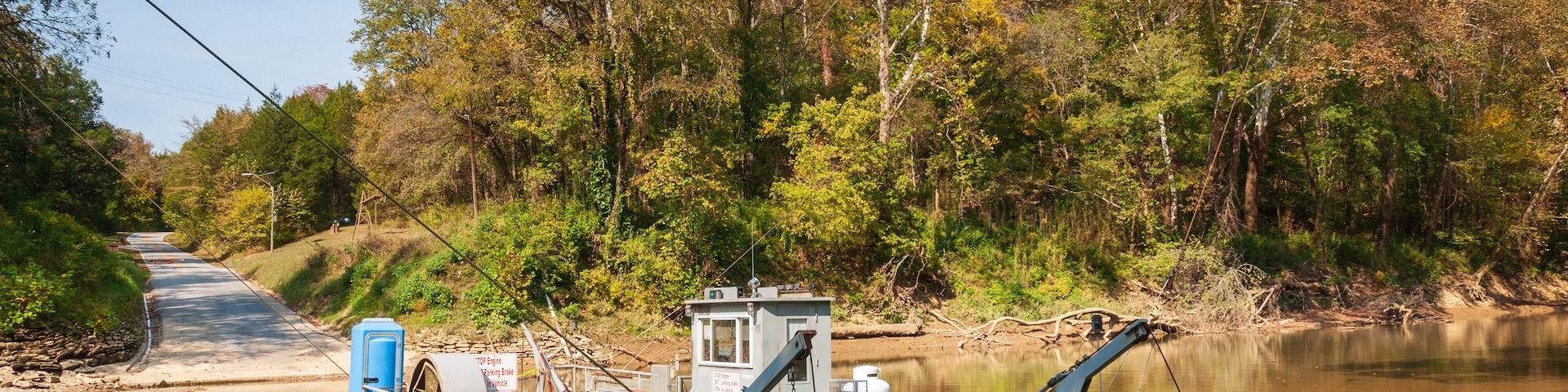 A river with a dock, a small building, and trees in the background.