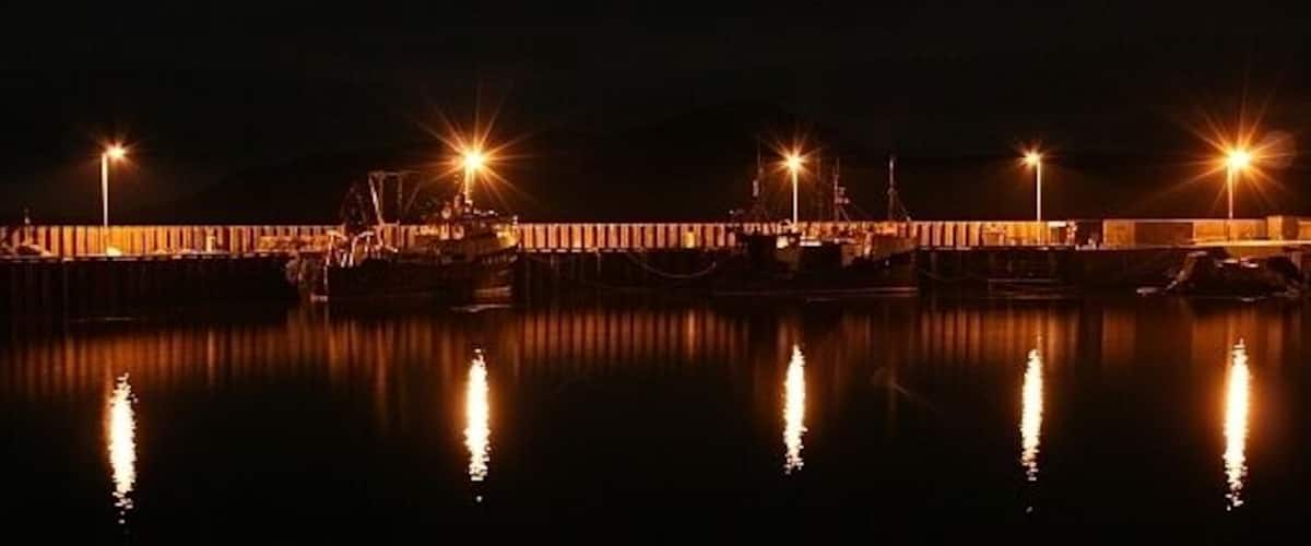 A nighttime harbor with boats and illuminated structures.