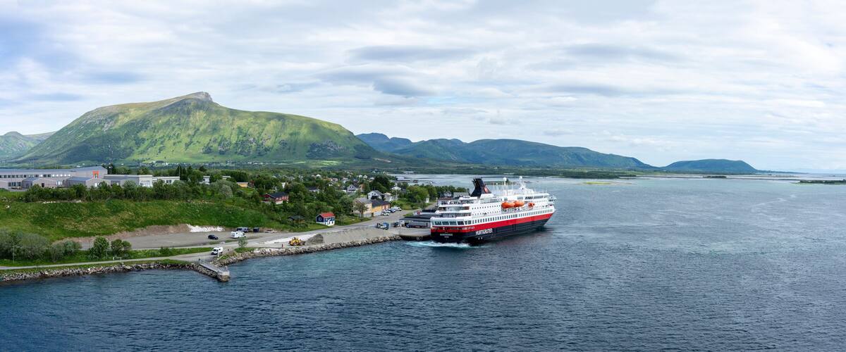A ferry docked at a harbor with a mountainous backdrop.