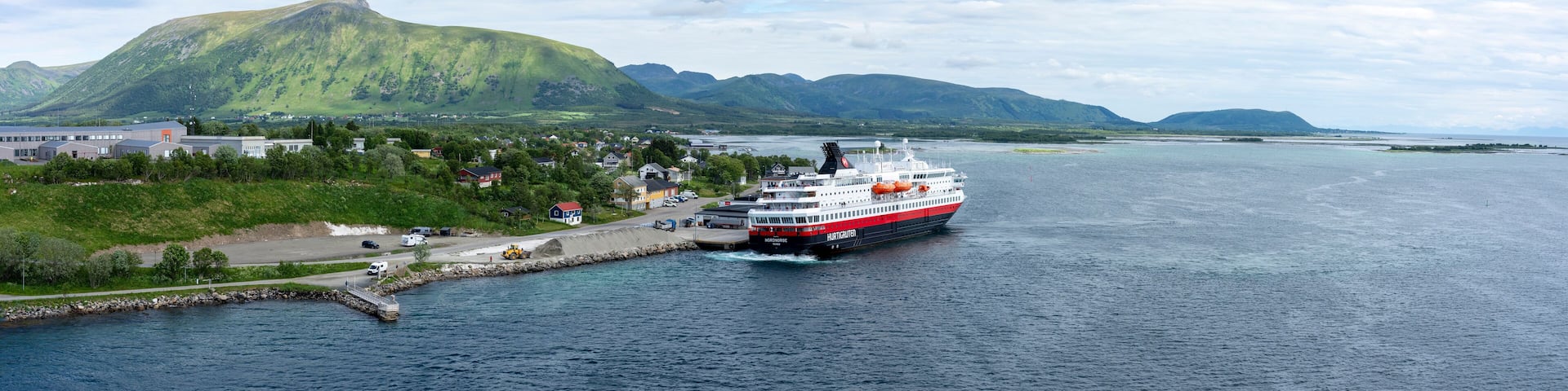 A ferry docked at a harbor with a mountainous backdrop.