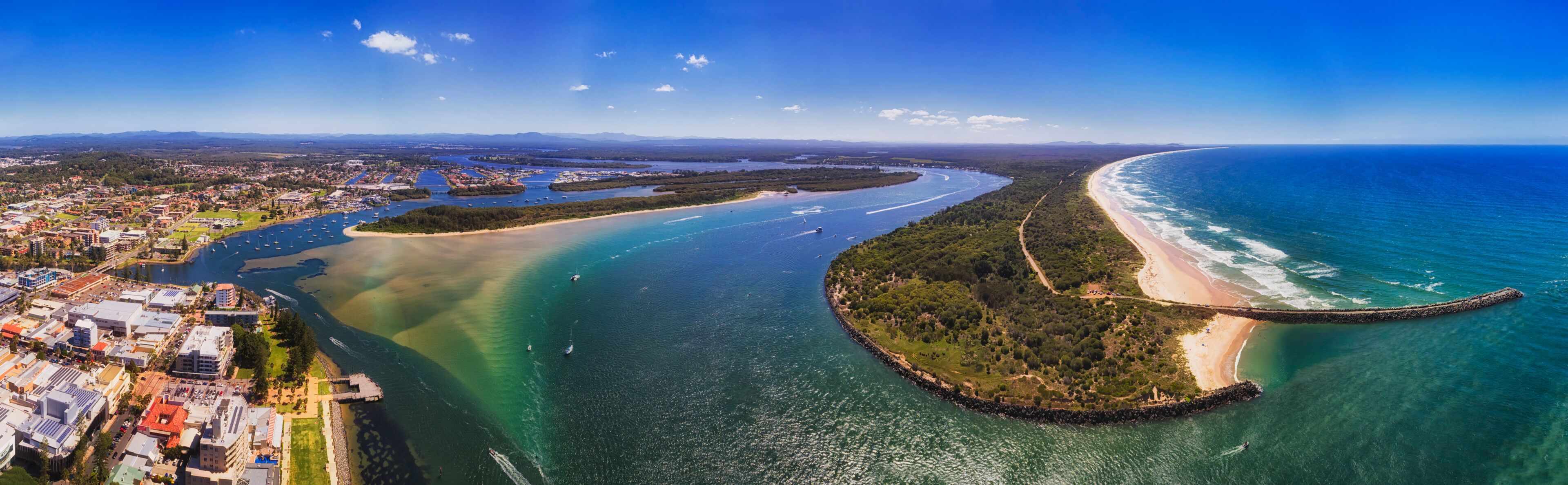 A coastal city with a bay, a beach, and a peninsula with dense vegetation.