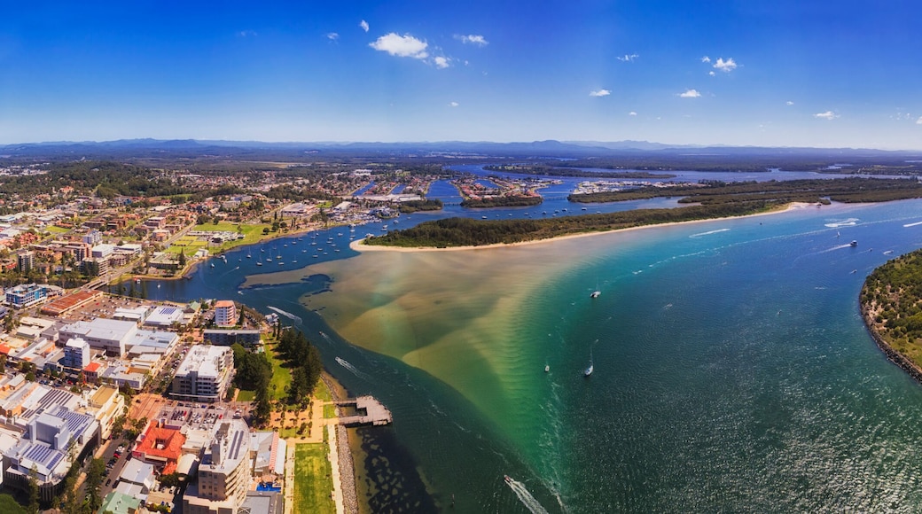 A coastal city with a bay, a beach, and a peninsula with dense vegetation.