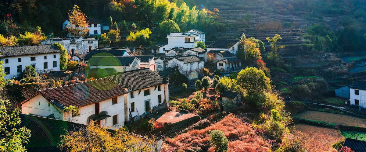 A village with traditional houses nestled in a hilly landscape with terraced fields.