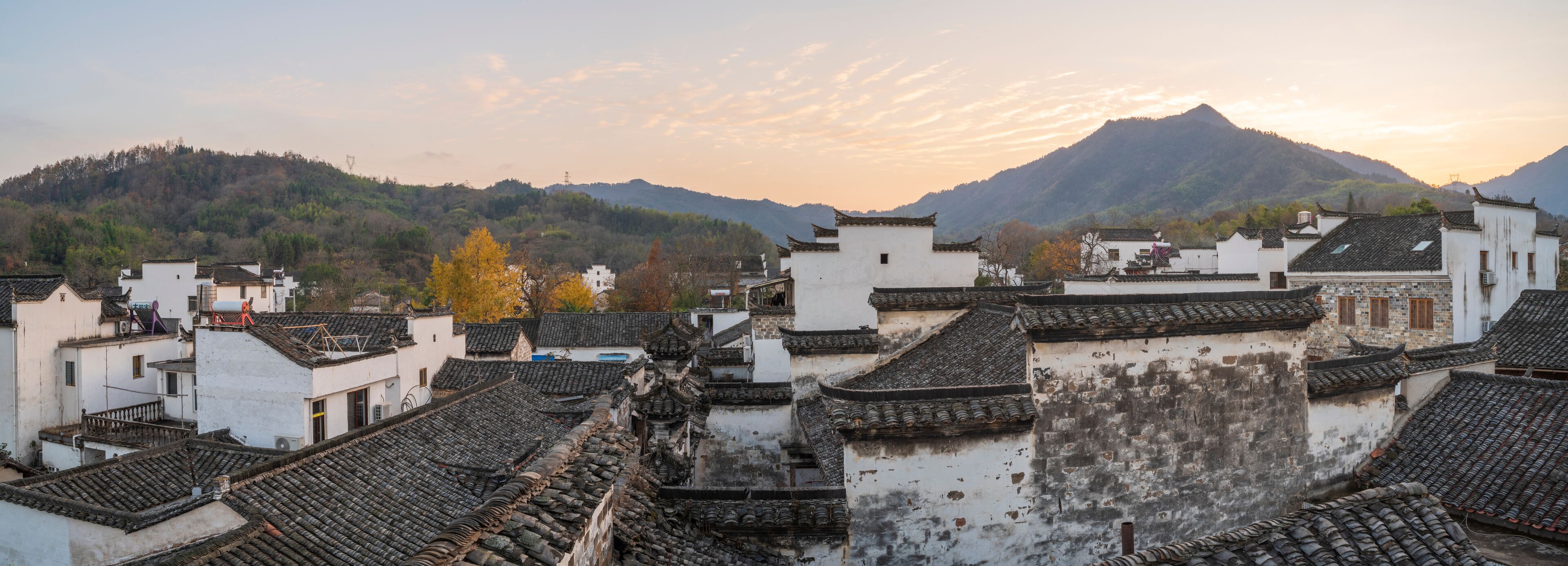 A traditional village with tiered roofs and a mountain in the background.