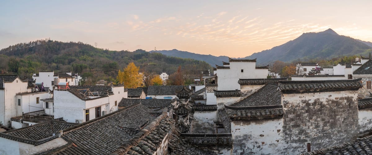 A traditional village with tiered roofs and a mountain in the background.