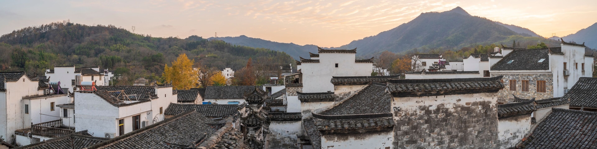A traditional village with tiered roofs and a mountain in the background.