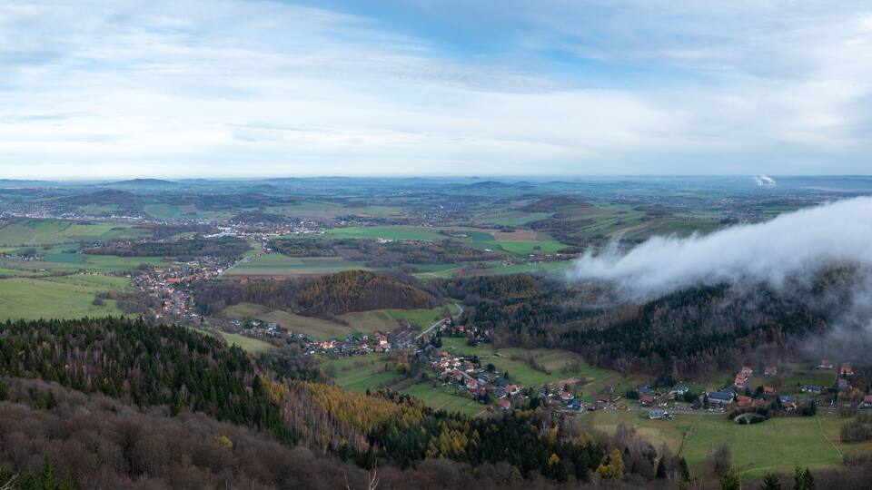 A valley with a small town surrounded by hills and forests.
