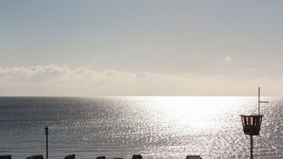 A beach with a row of empty chairs and a lifeguard tower.