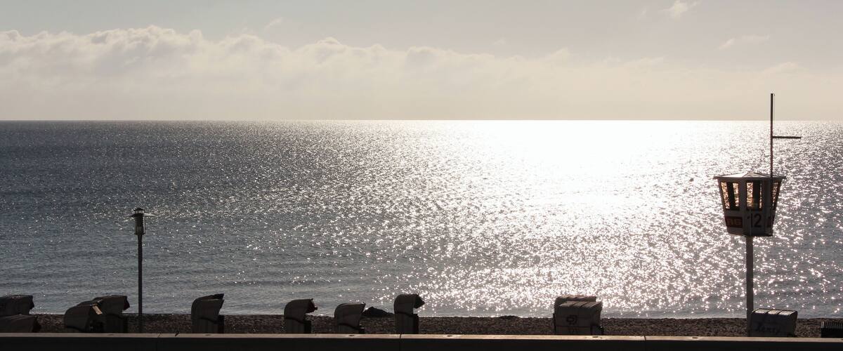 A beach with a row of empty chairs and a lifeguard tower.