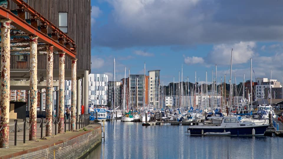 A marina with numerous boats docked, a modern building with peeling paint, and a clear sky.