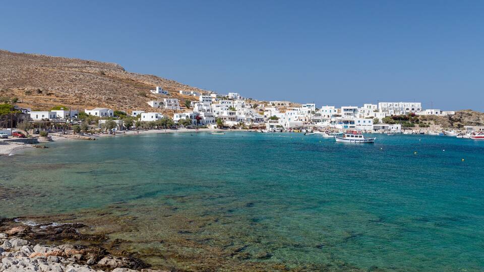 A coastal town with white buildings, clear turquoise waters, and boats.