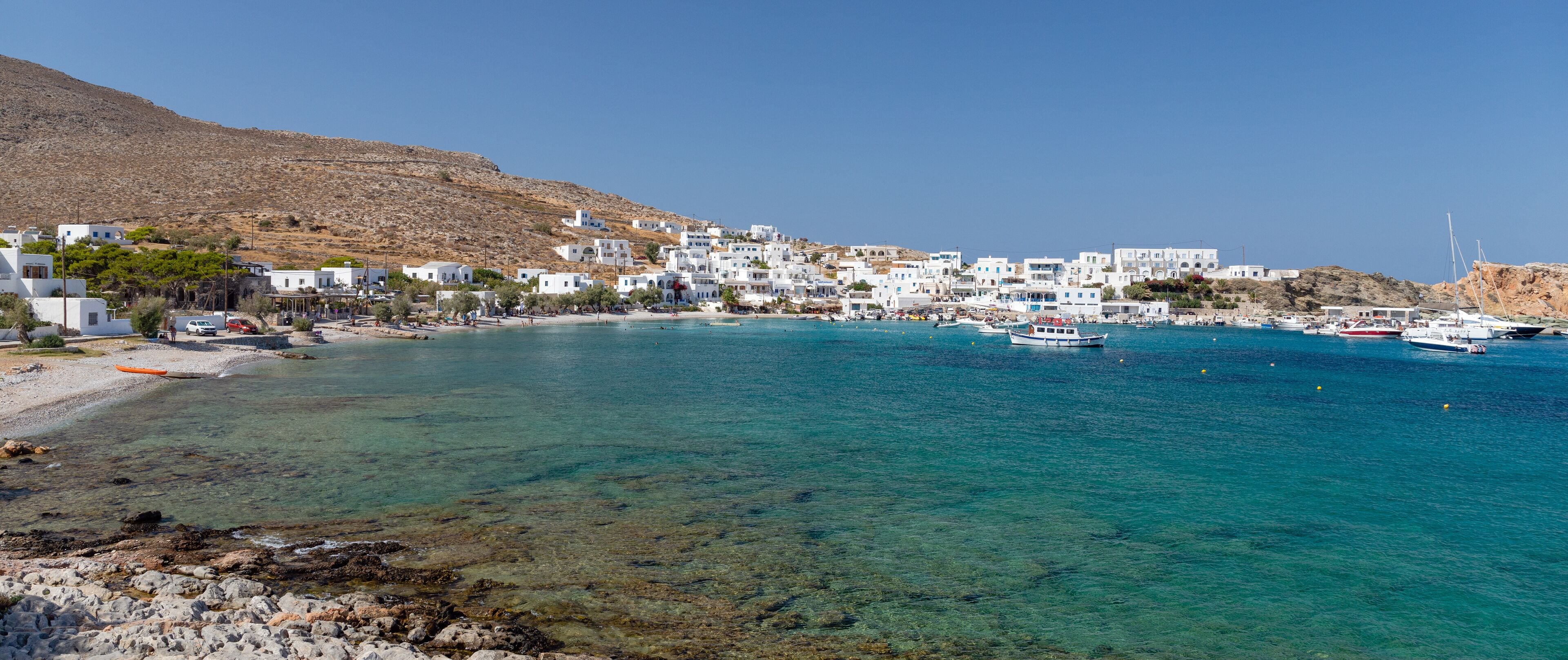 A coastal town with white buildings, clear turquoise waters, and boats.
