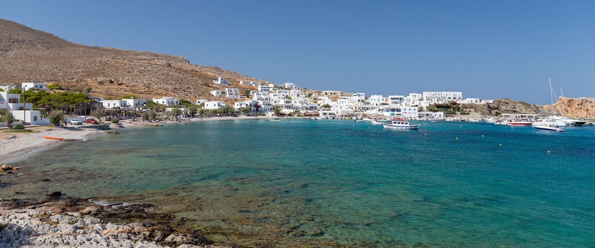 A coastal town with white buildings, clear turquoise waters, and boats.
