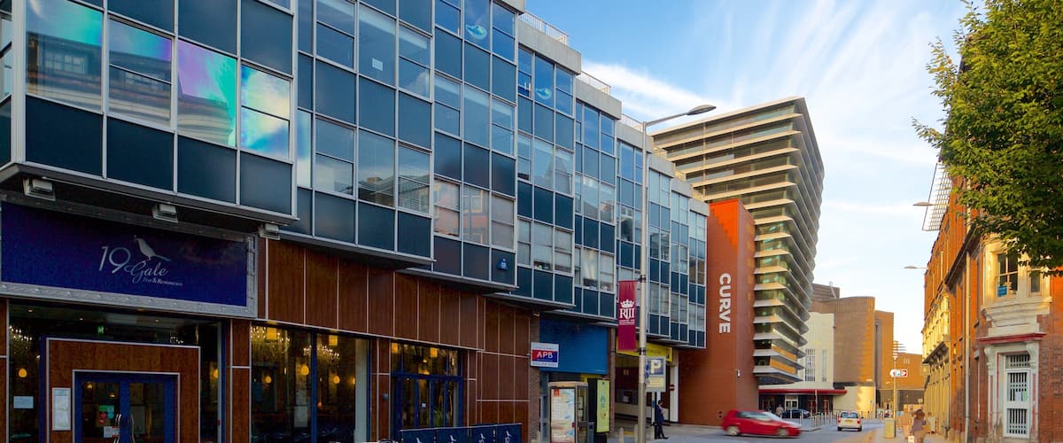A modern urban street with a mix of commercial buildings, including a restaurant named '19 Gate' and a building with 'CURVE' signage.