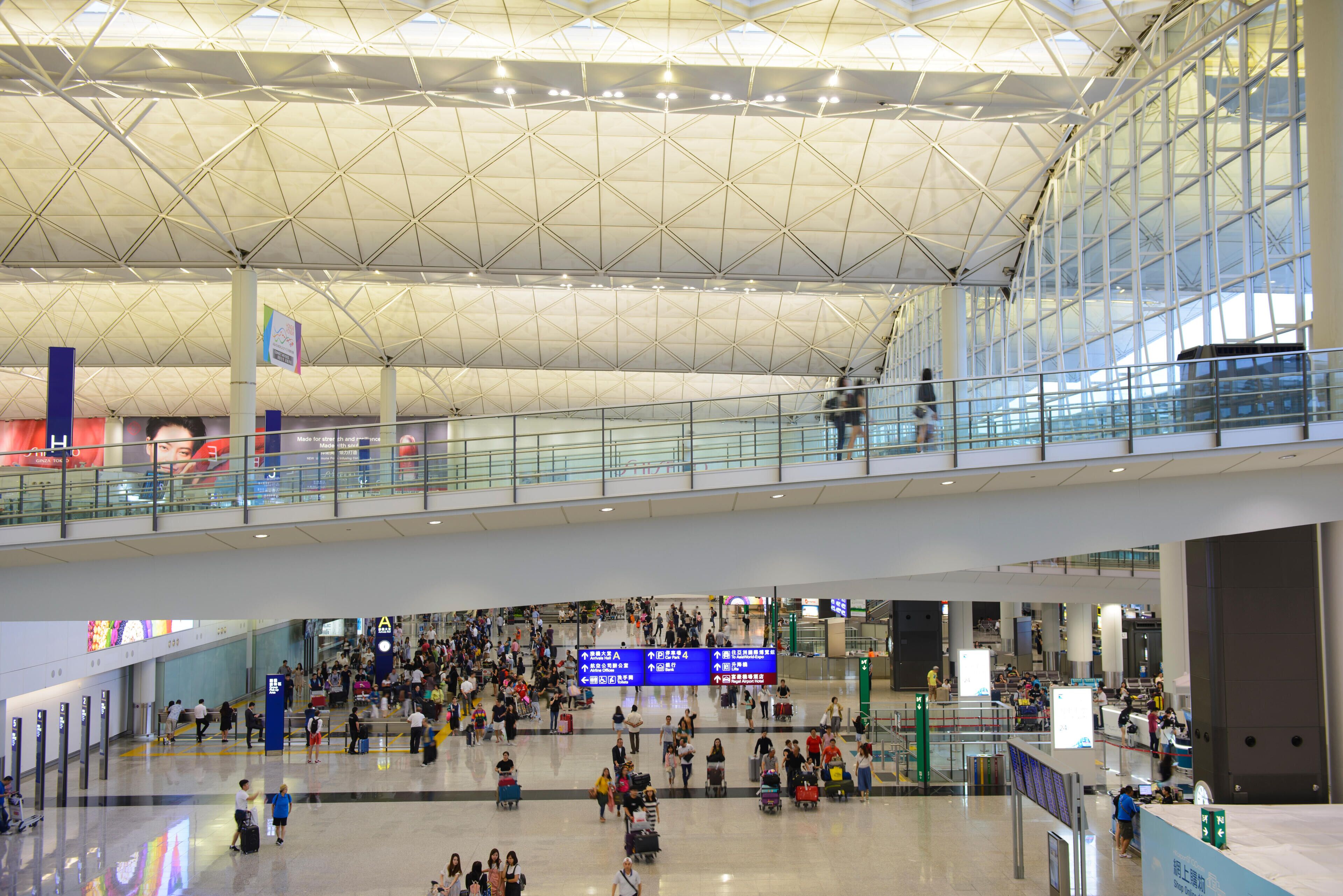 A spacious airport terminal with a high ceiling and glass railings.