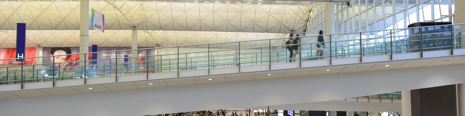 Um terminal de aeroporto espaçoso, com teto alto e guarda-corpos de vidro.