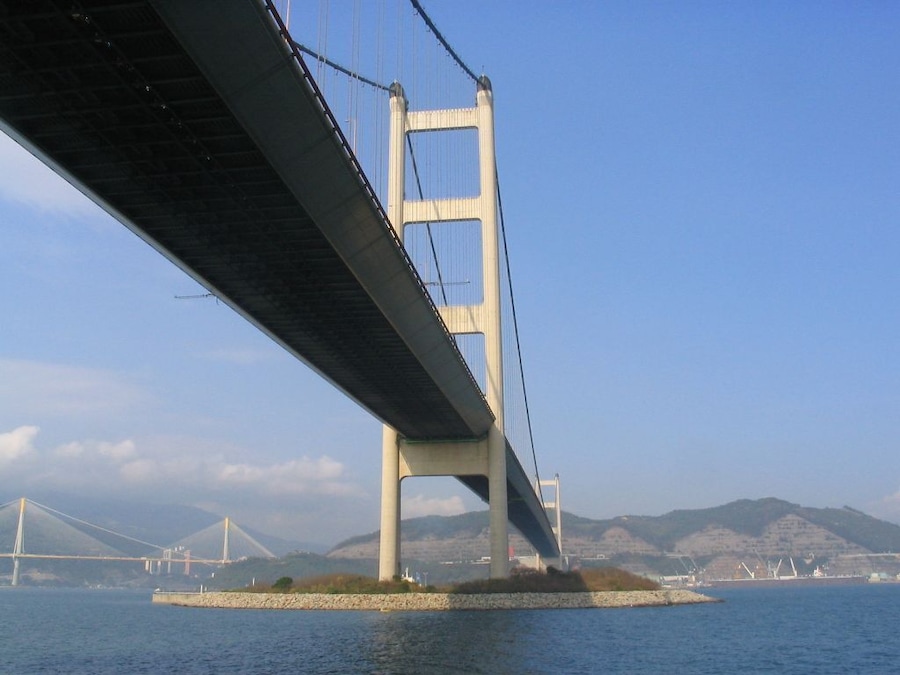 Un puente colgante con una vista despejada del agua y montañas a lo lejos.