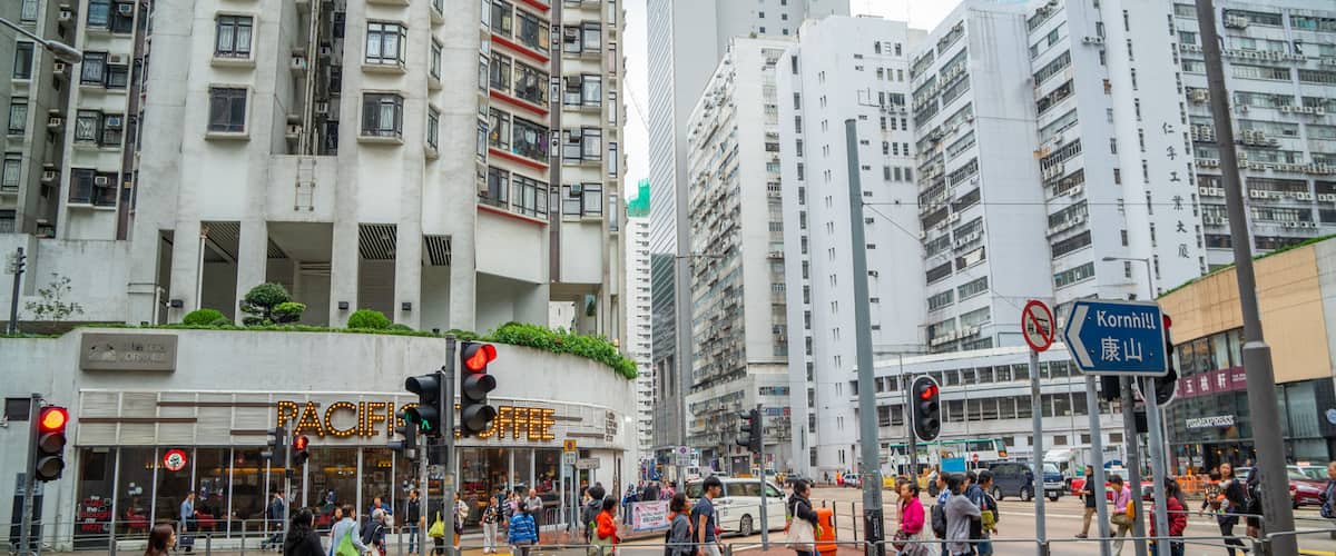 A busy urban street with pedestrians crossing, traffic lights, and high-rise buildings.