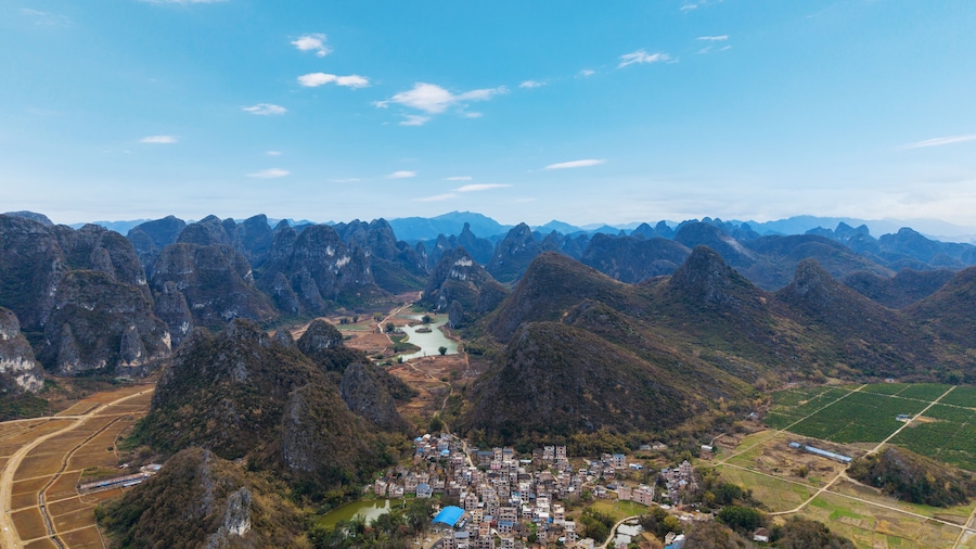 A mountainous landscape with a river, a village, and agricultural fields.