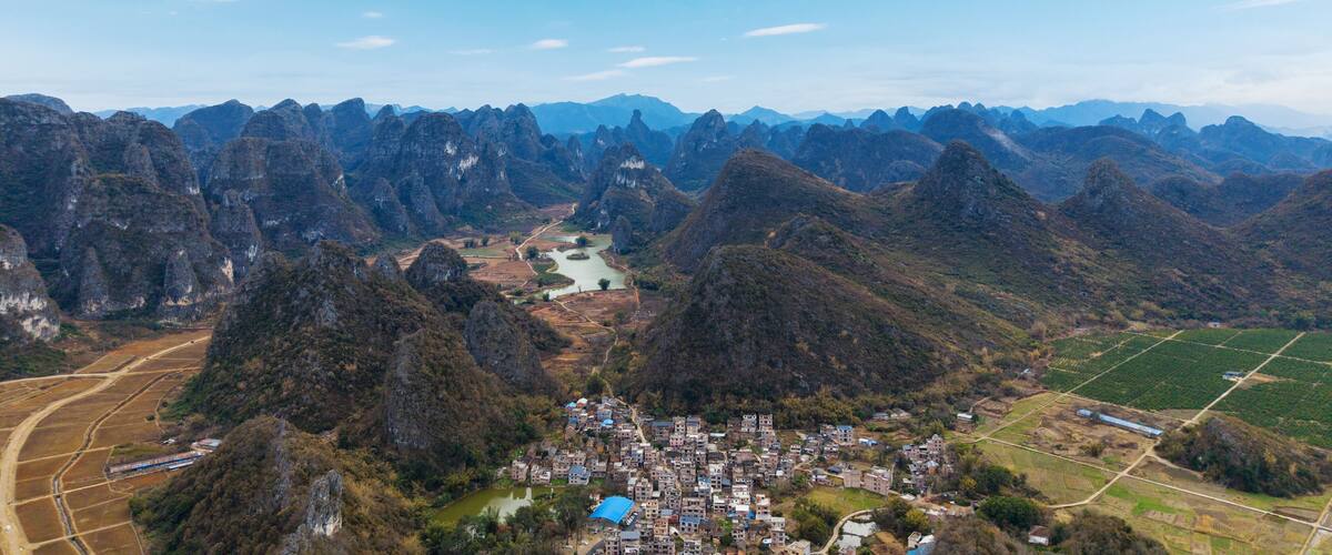 A mountainous landscape with a river, a village, and agricultural fields.