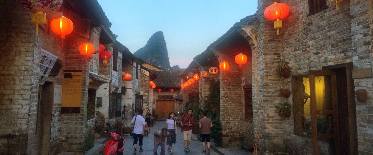 A narrow street flanked by traditional brick buildings with red lanterns hanging overhead.