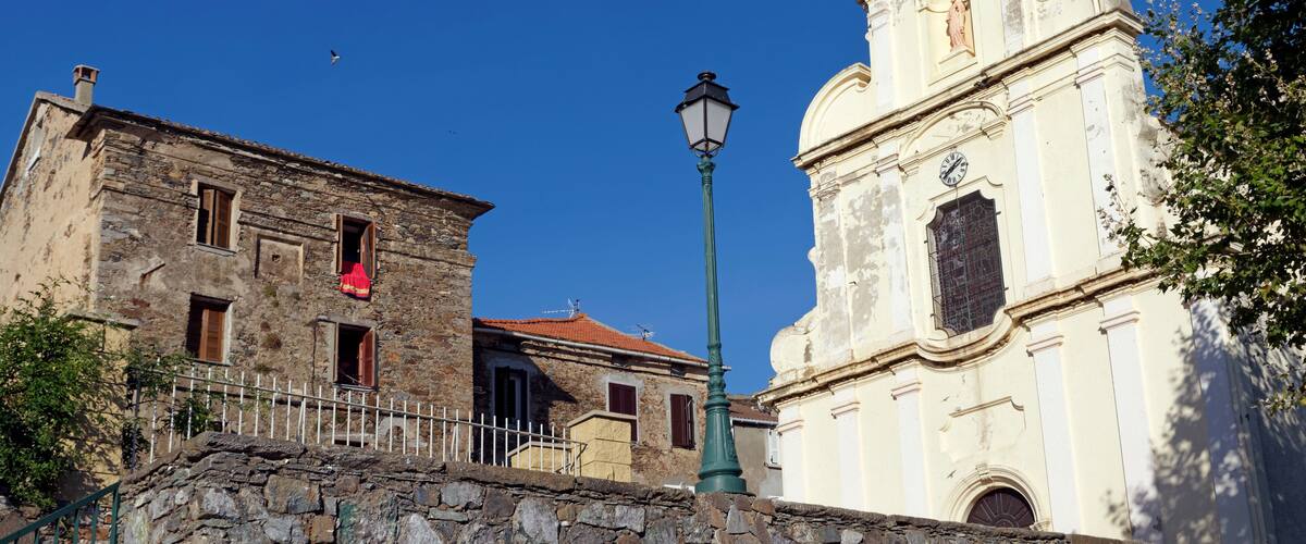 A historic building with a stone facade and a white church with a bell tower.