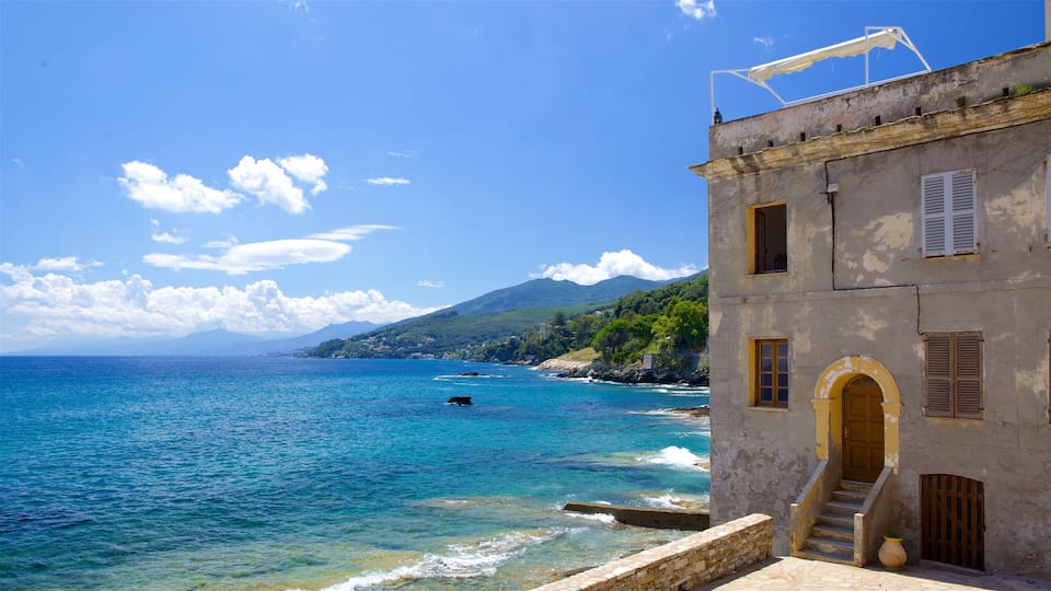 A coastal building with a clear view of the sea and a mountainous backdrop.