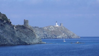 A rocky coastline with a lighthouse and a tower on a small island.