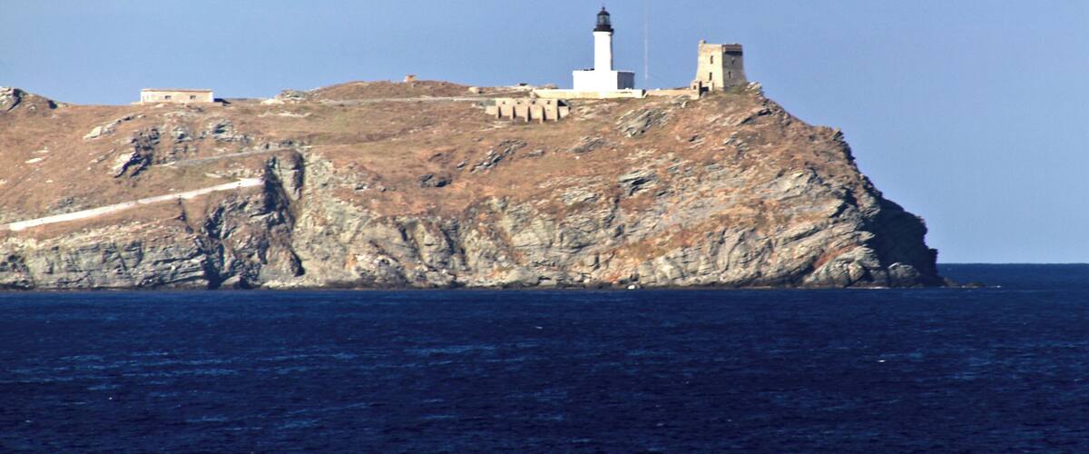 Un phare situé sur une falaise rocheuse, en bord de mer, offrant une vue dégagée sur l’océan.