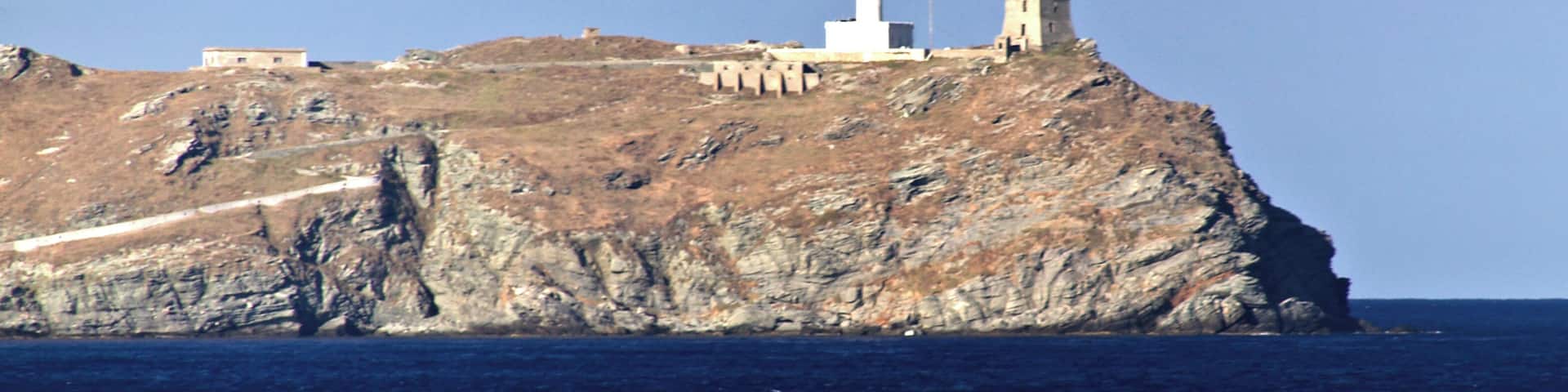 A coastal lighthouse on a rocky cliff with a clear view of the sea.