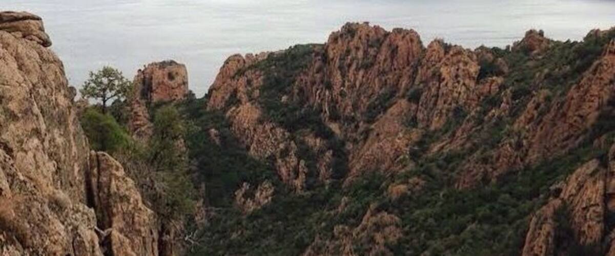 Rugged cliffs, dense greenery, and a distant body of water.