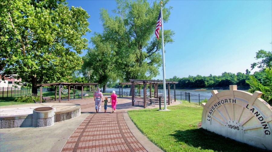 Un parque con un pabellón, un área de juegos, un cartel grande que dice 'LEAVENWORTH LANDING 1996' y un río al fondo.