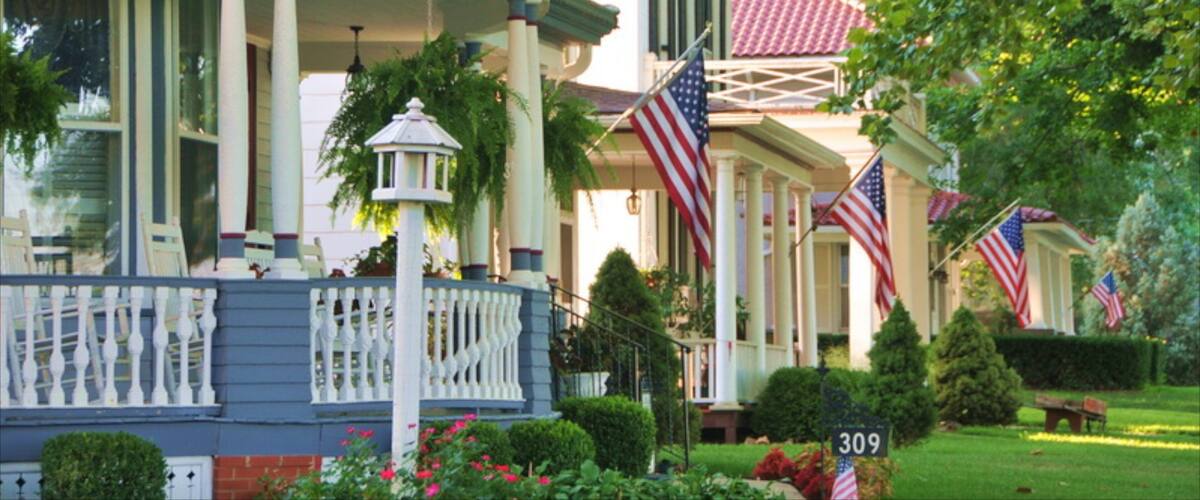 A row of stately homes with American flags, a well-manicured lawn, and a street sign with the number 309.