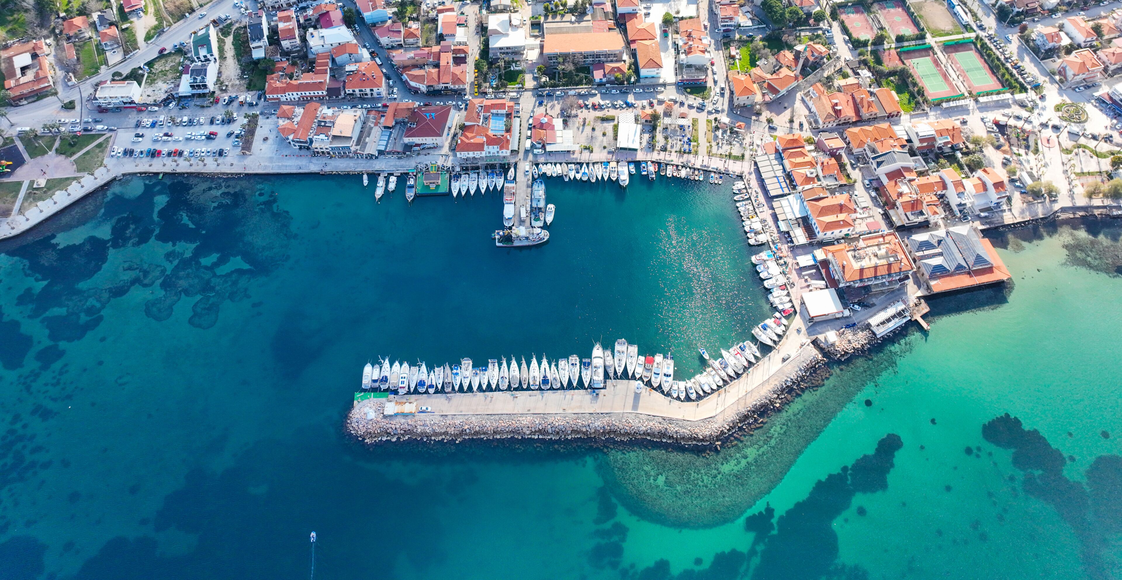 An aerial view of a coastal town with a marina, boats, and buildings.