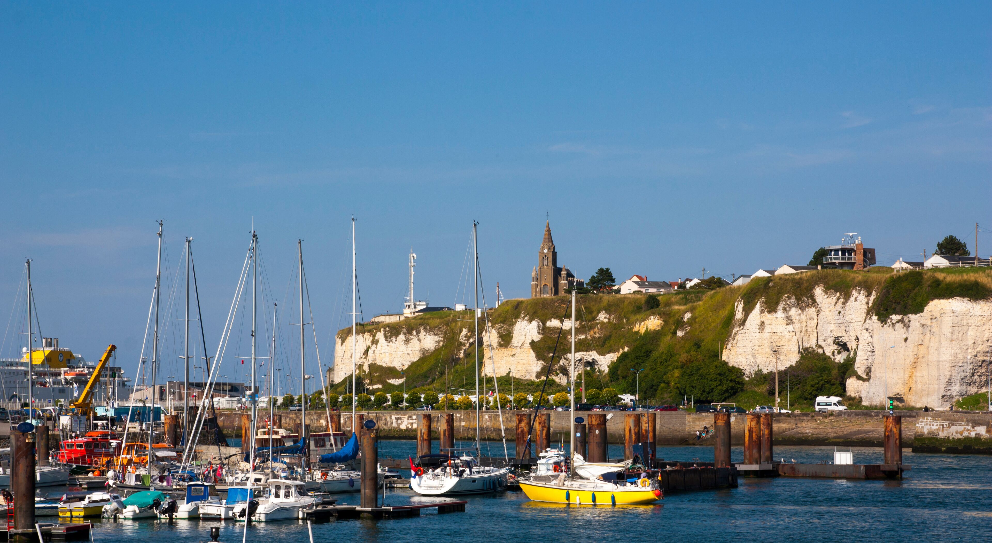A harbor with boats, a church, and cliffs.