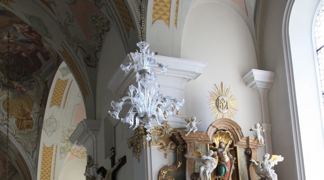 Italy, South Tyrol, Gossensaß. The church is dedicated to the Immaculate Conception and was built in 1750 on the same place of the old gothic church erected in 1471 and dedicated to Saint George of which remains the bell tower. The church was built on design of Franz de Paula Penz in baroque, it is possible a former project by Johann G. D. Grasmair. The church was consecrated on July 4 and 5, 1754 by bishop Leopold von Spaur. The front shows the portal of the old church and the three niches in which are placed the statues of the Immaculate Conception, Joachim and Saint Anne. The nave has a cross shape with two arms forming four lateral chapels. The high altar is rich in golden shades and at the centre of the throne is placed the statute of the Immaculate with the child was installed on April 23, 1752 by Josepf Stapf. The four statues are: St. George, St. Stephen, St. Lawrence and St. Florien. To the left side, between the two lateral chapels, is the baroque pulpit of 1777 positioned in a central site. To the right side between the two lateral chapels is a Crucifix by Bartlmä Kleinhans. The first right lateral altar is dedicated to Our Lady of Sorrows encircled by the statues of Mary Magdalene, Saint Elisabeth and Saint James works of 1750. The second right lateral altar is dedicated to Francis Xavier and two Bishops: Saint Ingenuinus and Saint Albuin coming from the old Saint George church. The first left lateral altar is the Flagellation of Christ at the column and the Saints Peter and John on each side. To the second left lateral altar is Saint Leonard, by side are the statues of Saint Sylvester, Saint Gregory and Saint Barbara coming from the old church. The eastern dome fresco was painted by Matthäus Günther and represents the Christ crowning Mary and Saint George throwing the pierced dragon downwards.